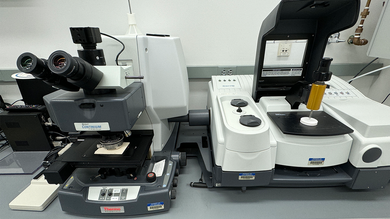 Two large microscopes next to each other on a grey table.