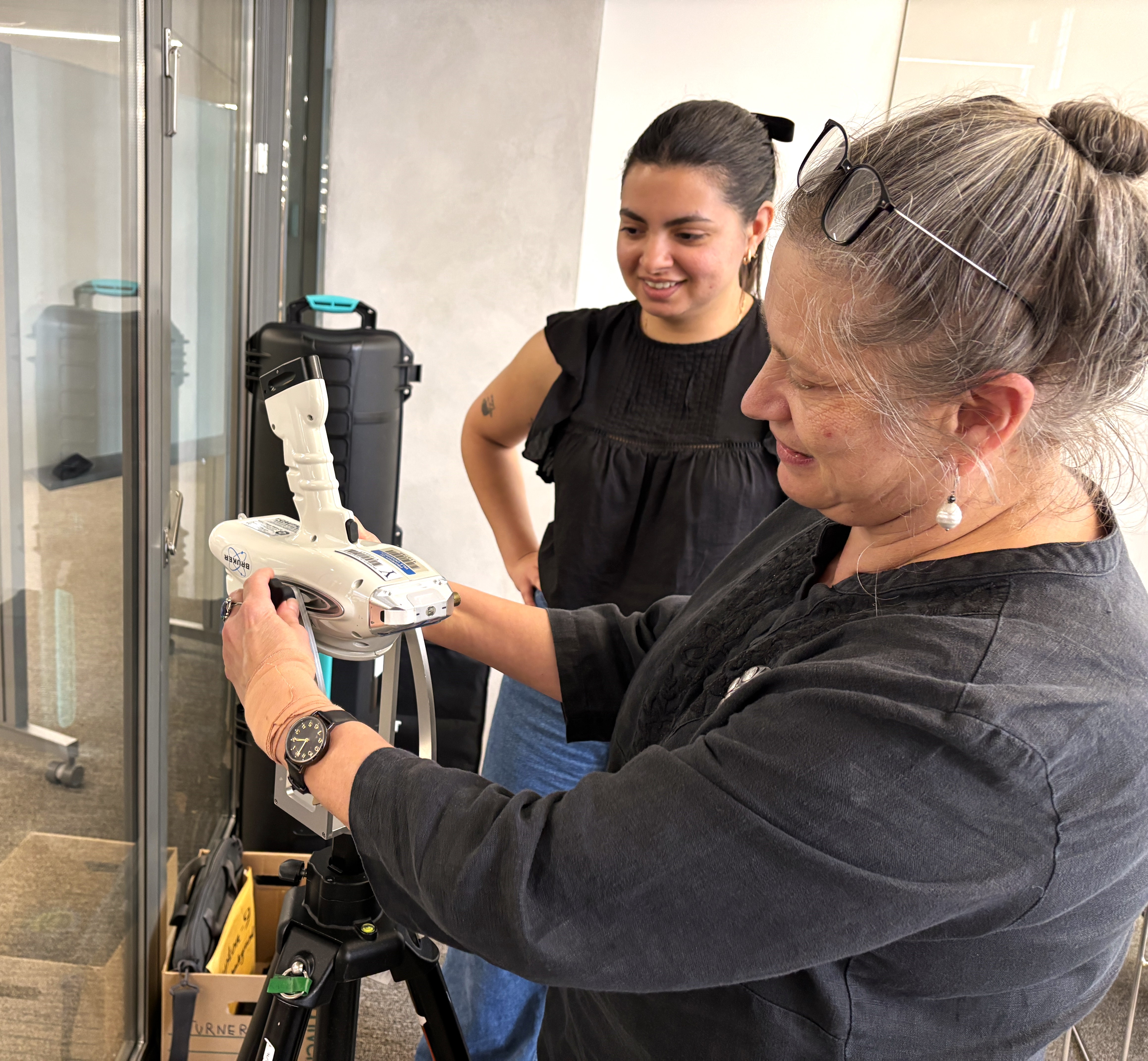 Two woman set up a handheld XRF. 