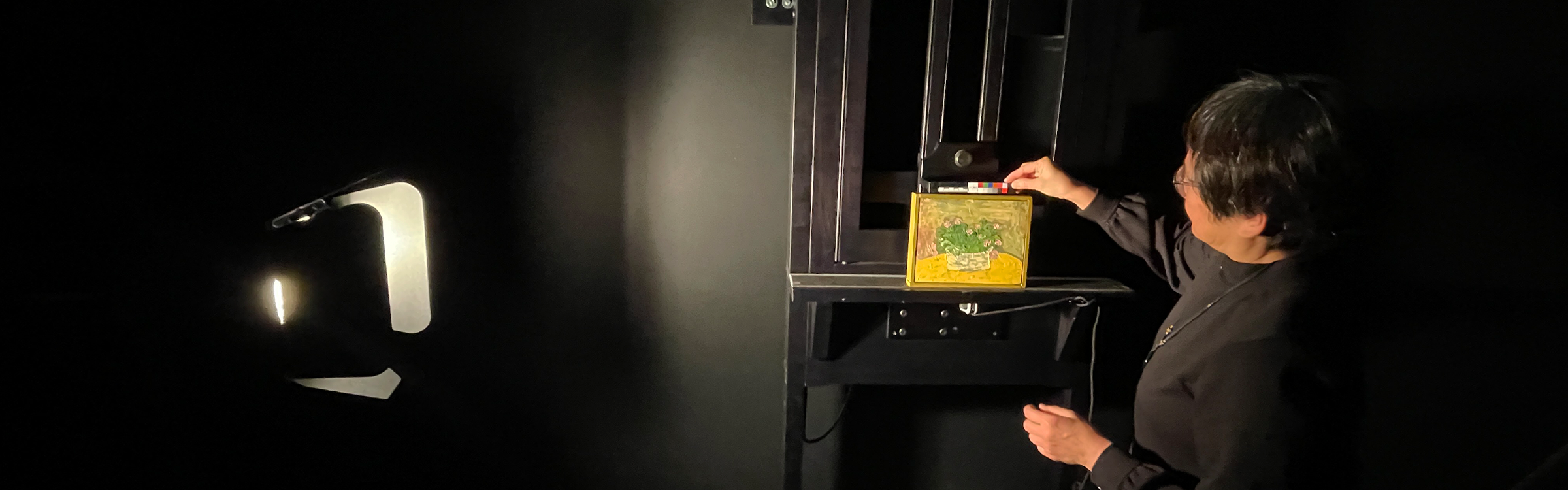 Jiuan Jiuan Chen uses a raking light technique on a small yellow painting. 