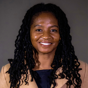A woman with long dark braids smiles directly at the camera.