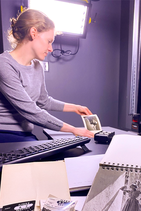 Individual in a photo studio holds an image with a vintage fashion magazine open to the viewer.