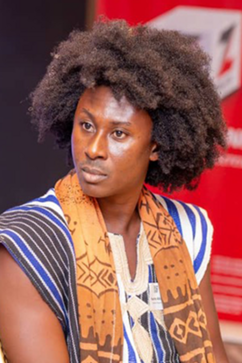 A man with dark skin and an afro looks intensely with colorful patterned clothing.