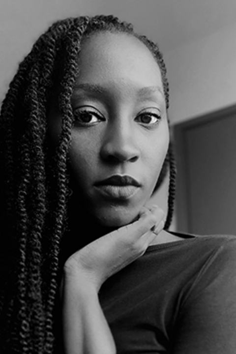 A black and white photo of a dark-skinned woman with long braids looking directly at the camera. 
