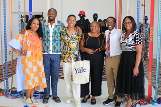 A group of individuals stand in a bright room smiling at the camera.