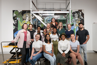 A class poses in front of a colorful painting. 