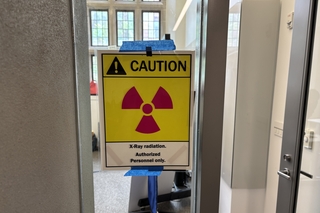 A yellow and red caution sign taped to a classroom window.