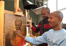 Racine Joseph (L) and Erntz Jeudy (R) surface cleaning a painting by Haitian artist Louis Rigaud 
