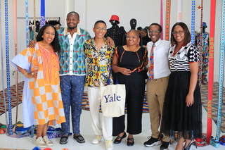 A group of individuals stand in a bright room smiling at the camera.