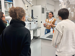A student presents to a group of peers in a science lab.