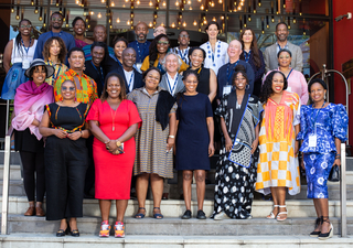 The 2024-25 cohort of Yale Directors Fellows stand in a group and smile at the camera.