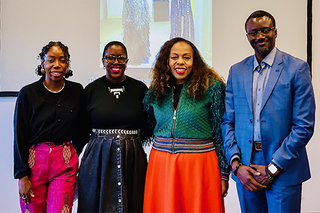 Four speakers stand together smiling at the camera.