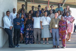A group of fellows stand on steps smiling at the camera.